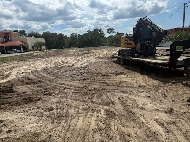 Two compact track loaders — Deere and Kubota — parked at a staging area
